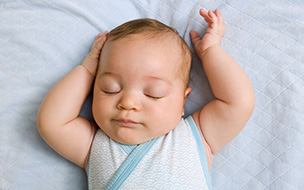 young infant lying on back with arms overhead