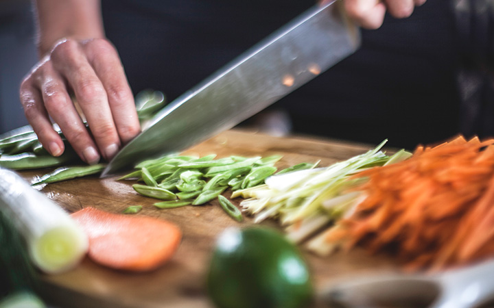 closeup of hands chopping vegetables with knife