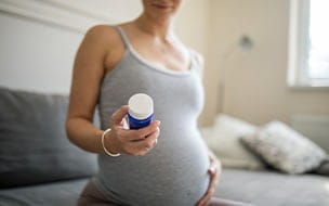 pregnant woman holds pill bottle