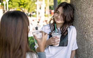 two teen girls drinking fancy coffee drinks
